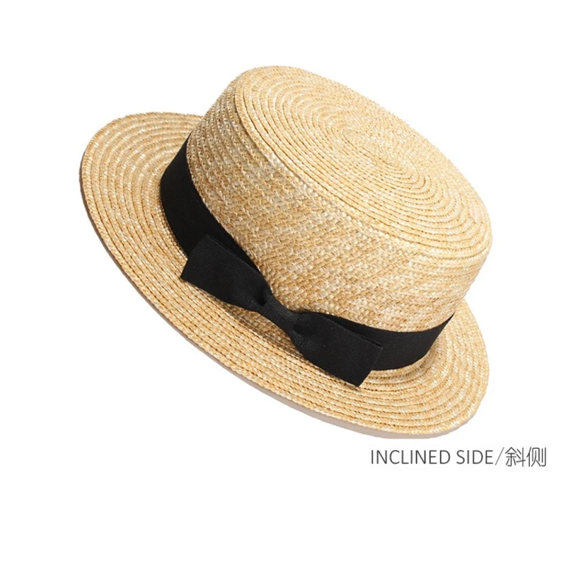 Wheat straw boater hat with black bow, angled view
