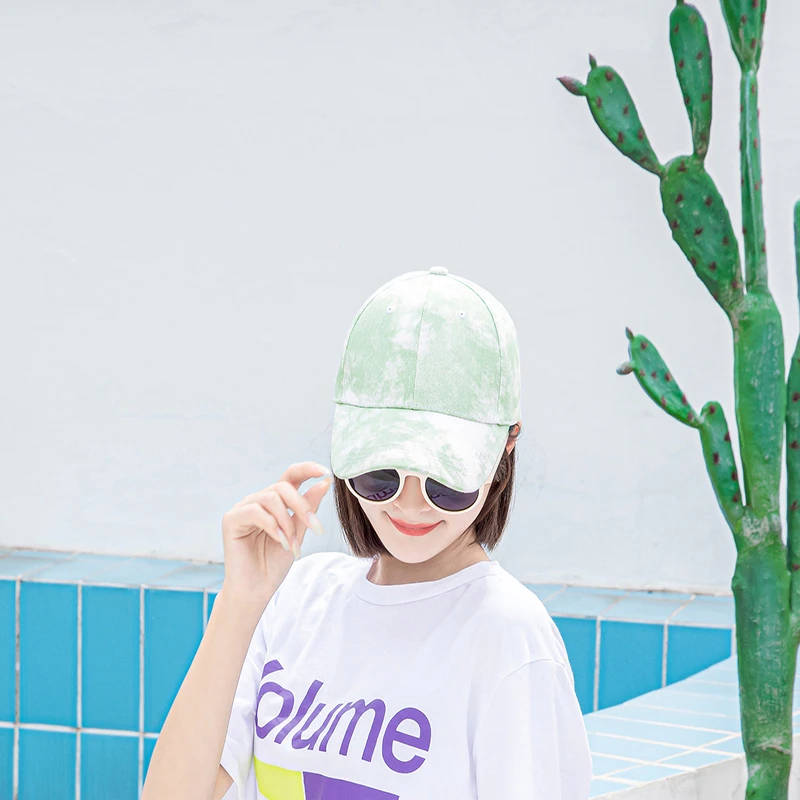 Woman wearing a green tie-dye cap with sunglasses