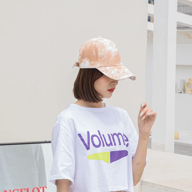 Woman wearing a peach tie-dye baseball cap